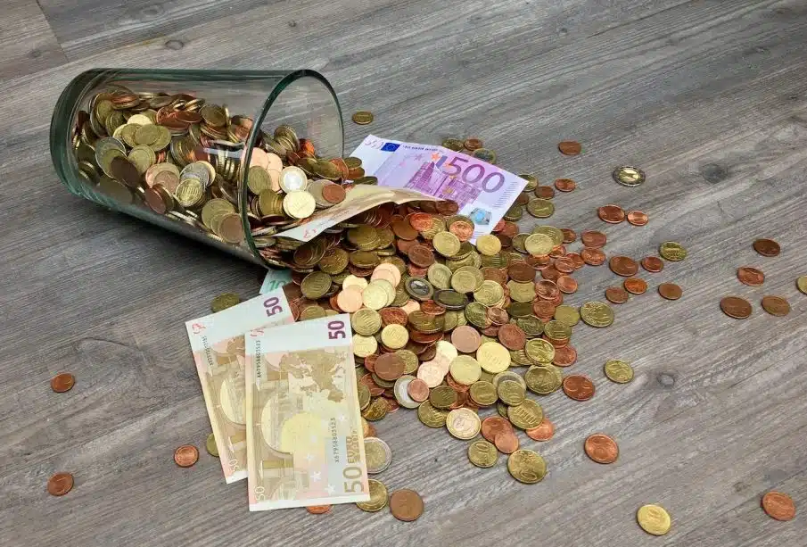 Coins and Banknotes Scattered on Gray Wooden Surface